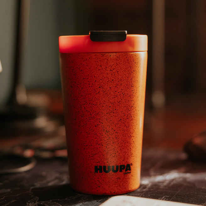 Termo naranja "Huupa" con fondo en casa borroso.