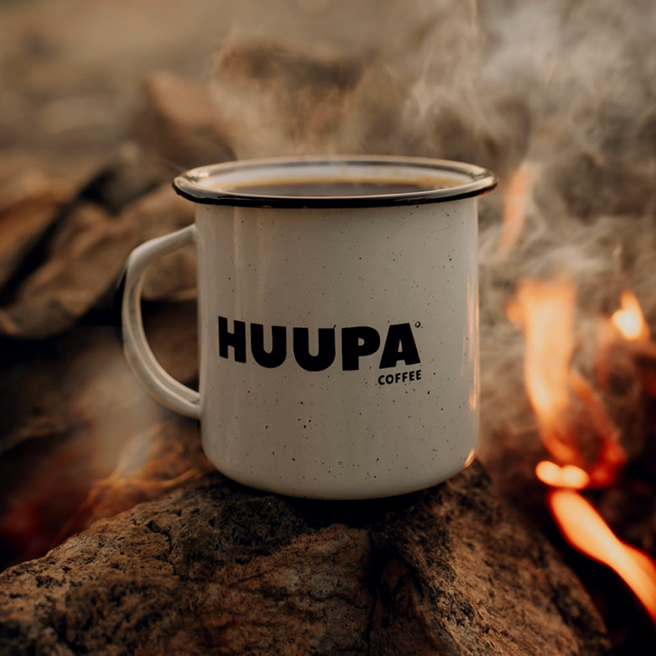 Taza blanca peltre "Huupa" sobre leña en fuego.