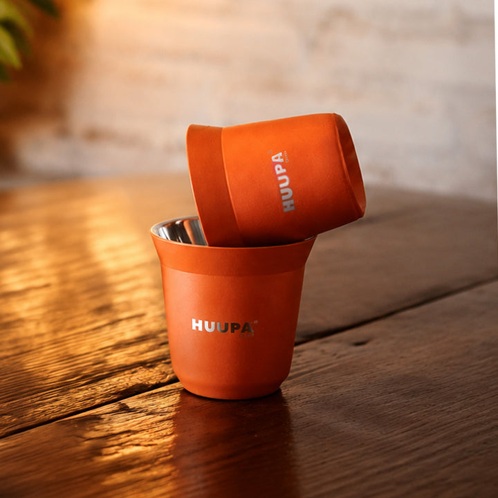 vaso medidor de espresso 80ml naranja marca HUUPA sobre mesa de madera