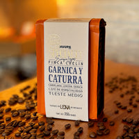 Bolsa de café de especialidad color naranja sobre ganos de café en mesa de madera.
